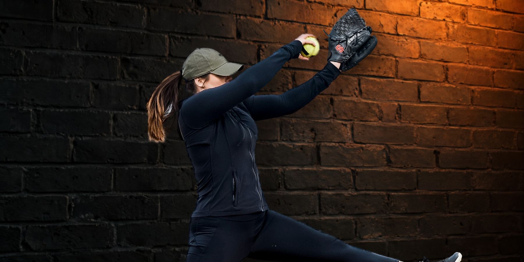 Nyree White pitching in front of a dark brick wall